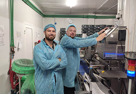 Two workers in blue protective gear in a factory